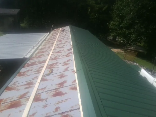 Old rusted panels beside newly installed green metal roofing — Wind Damage Roof Repair by Roofing Brothers in Cortland
