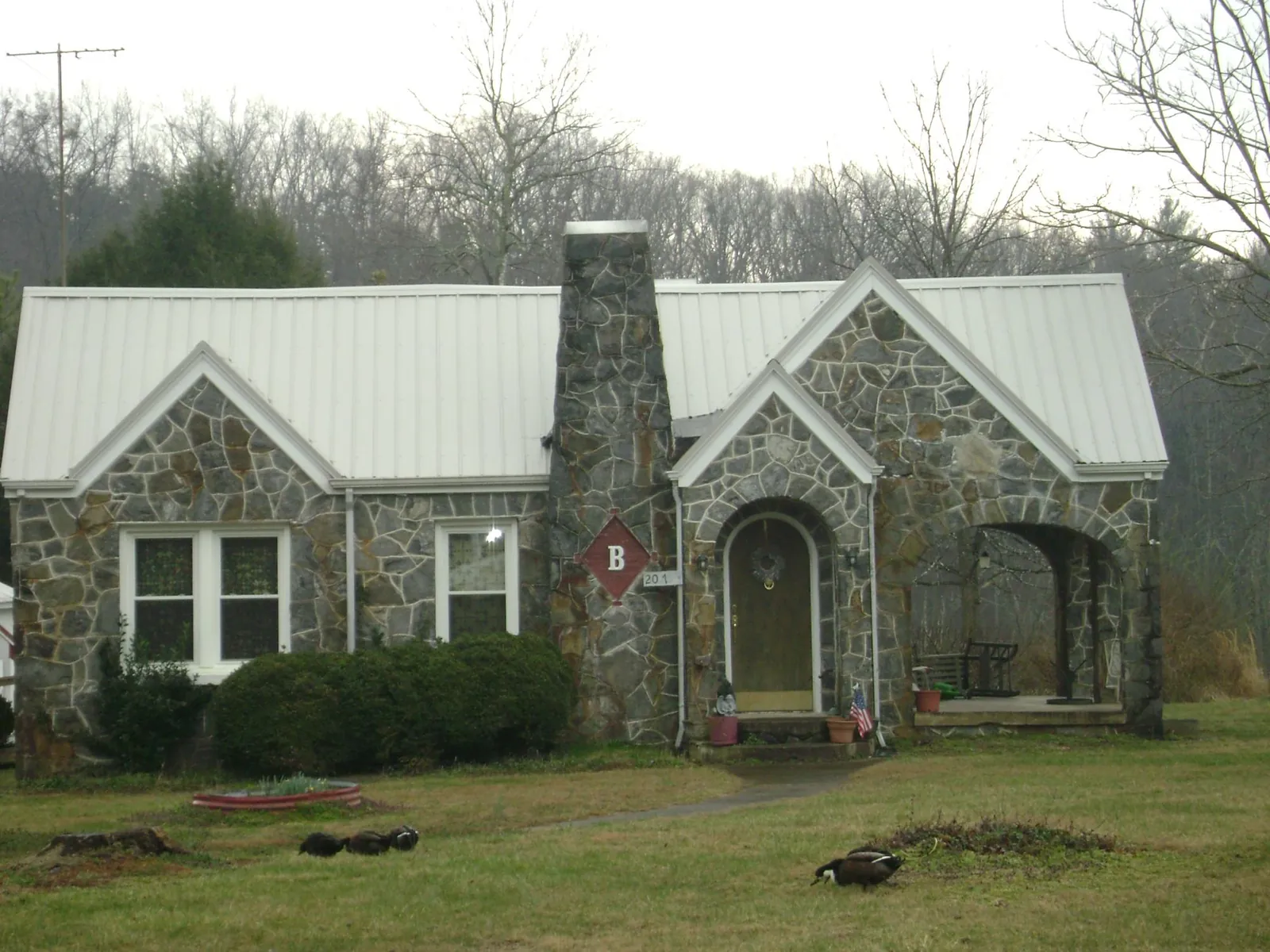 White metal roof on a stone cottage with steep gables in Cortland