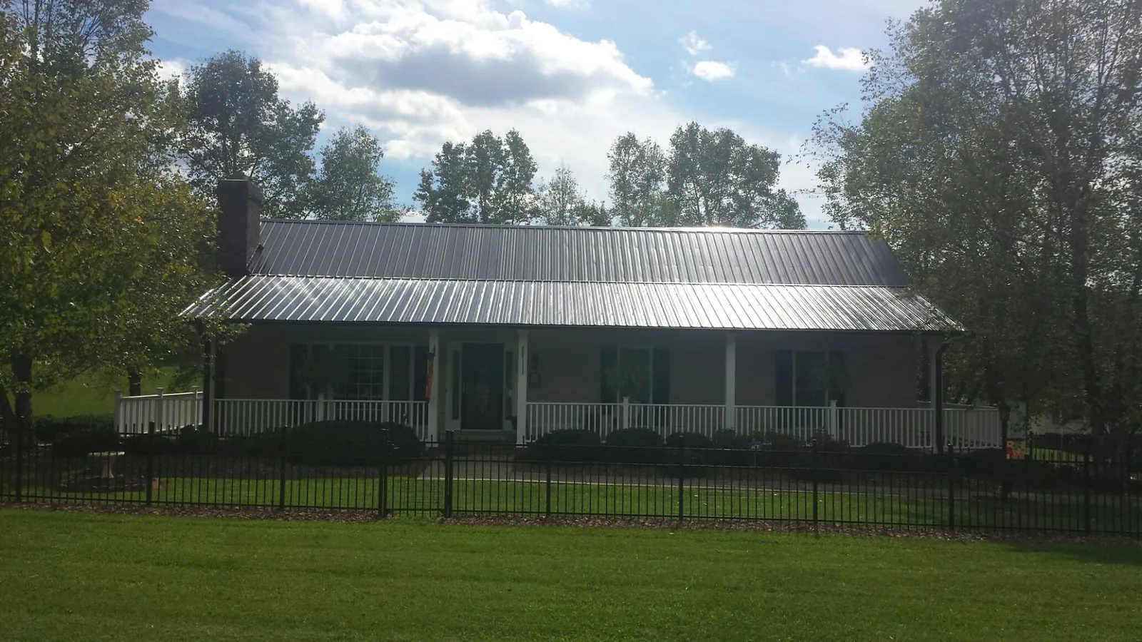 Gray metal roof on a brick ranch with a full width front porch — Gutter Guard Installation work by our crew in Cortland